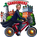 3D drewniany magnes z ruchomymi elementami przedstawiający Sandomierz – kolorowa grafika z charakterystycznymi budynkami miasta i postacią na rowerze. Pamiątka turystyczna, produkt B2B, POL-DSM-597.