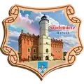 Drewniany magnes w kształcie ozdobnego suwoju z widokiem na Ratusz w Sandomierzu, produkt turystyczny na sprzedaż hurtową B2B, POL-DT-063.